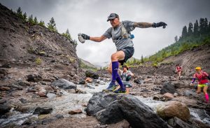Male athlete jumping over rocks