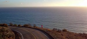 Athlete standing by bend in the road looking at the water