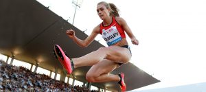 Colleen Quigley jumping over hurdle