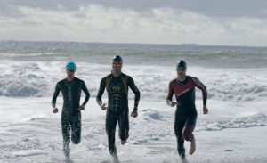 three athletes running out of ocean